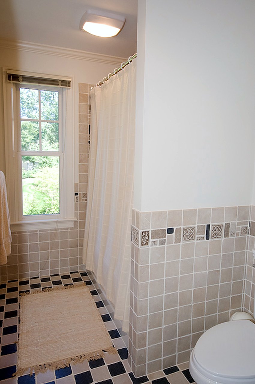 Bath with tumbled-stone wainscot, decorative inserts and a checkerboard floor
