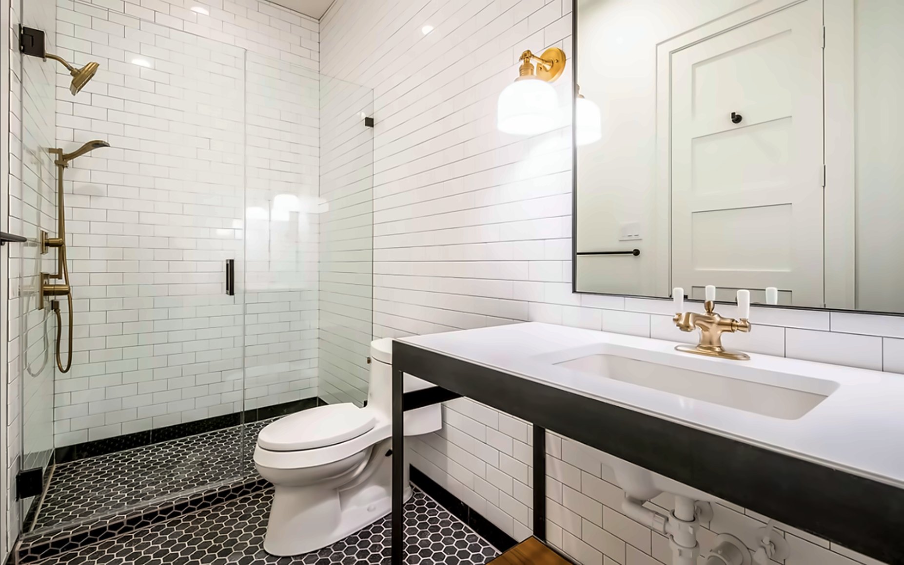 Bath with white subway tile, black hex floor and brass fixtures