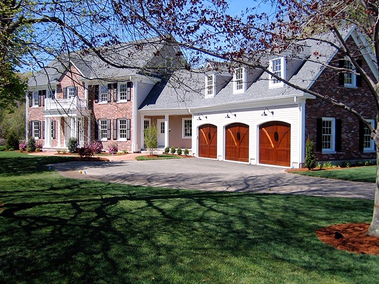 Brick colonial with dormers and three arched cedar garage doors