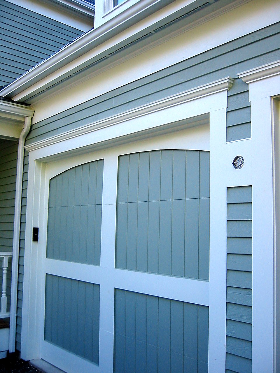 Carriage-style garage door with crown-molded trim and clapboard siding