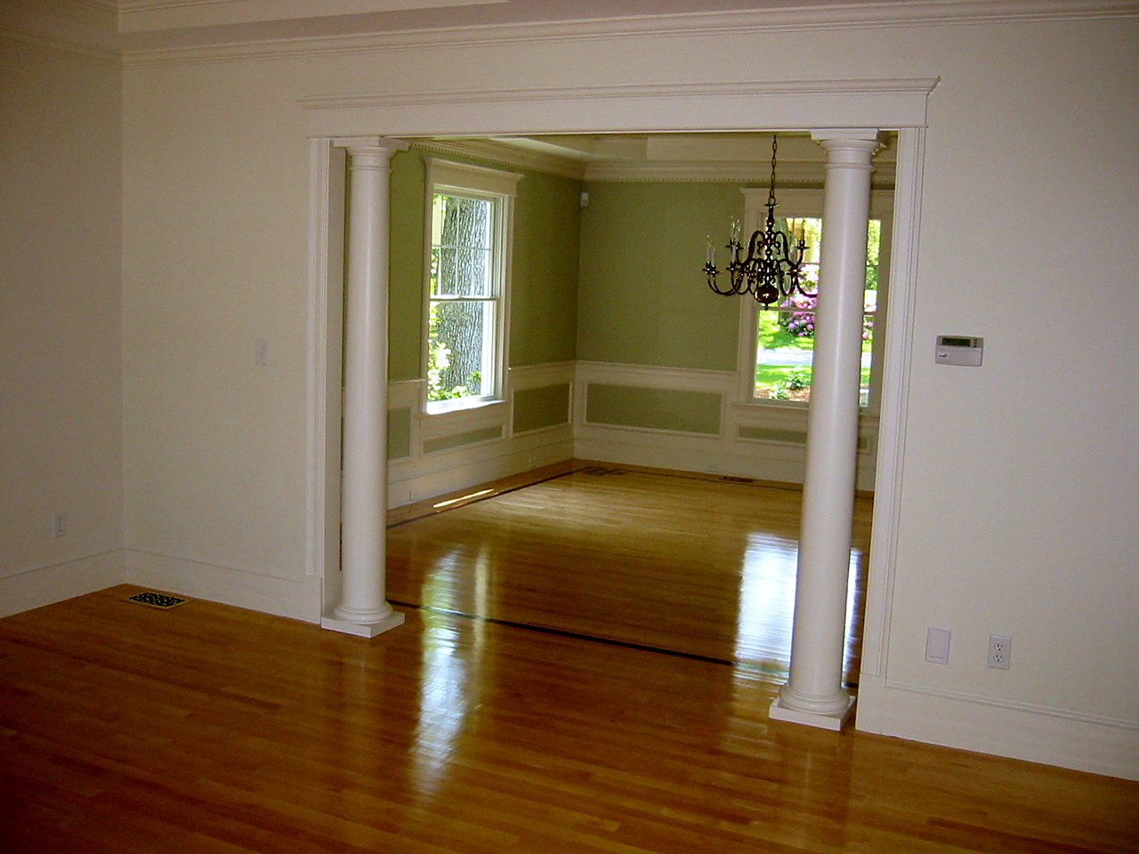 Cased opening with Tuscan columns looking into a paneled dining room