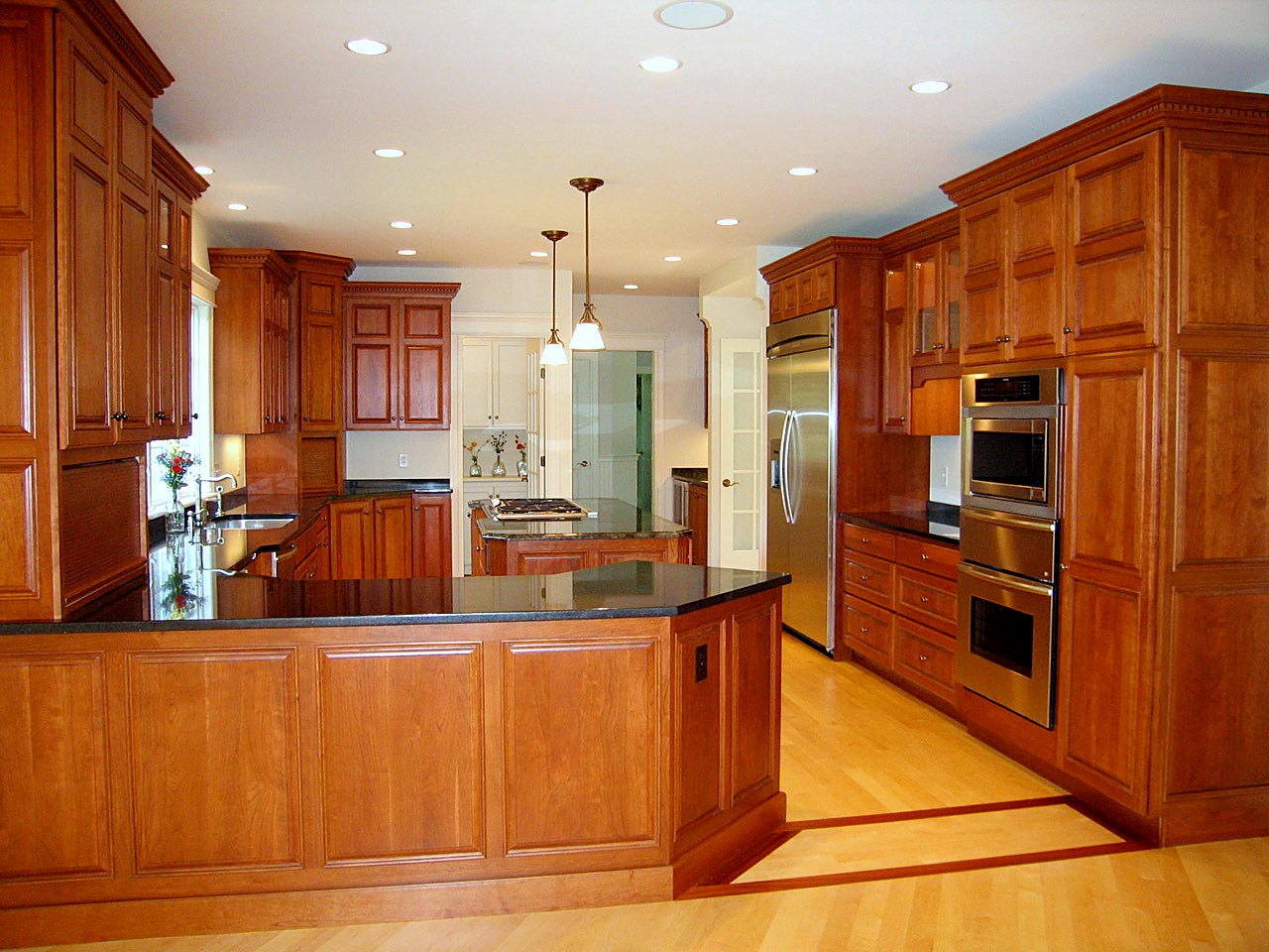 Cherry kitchen with raised-panel cabinetry, dentil crown and black granite counters