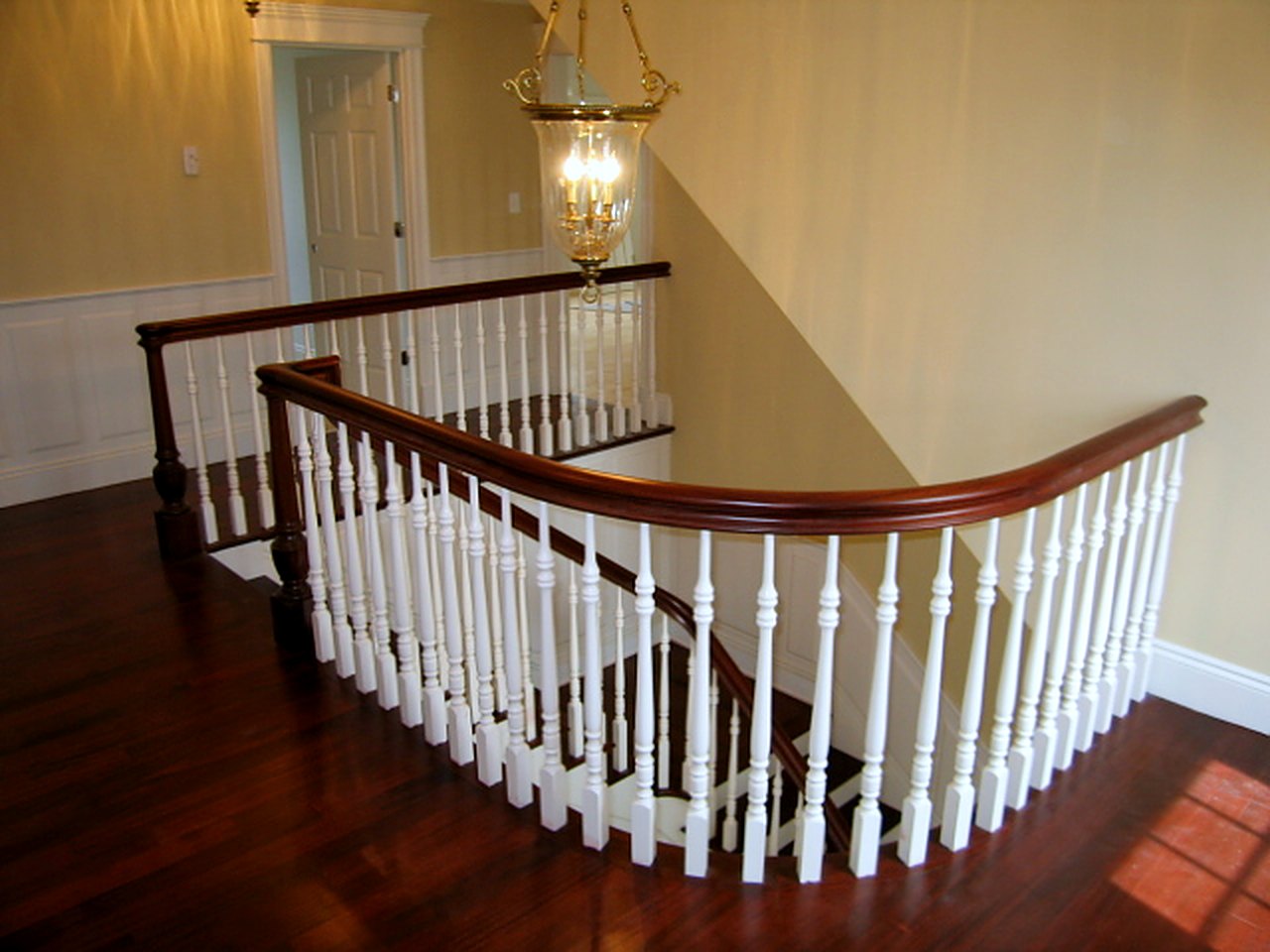 Curved landing rail with turned balusters over dark hardwood floors