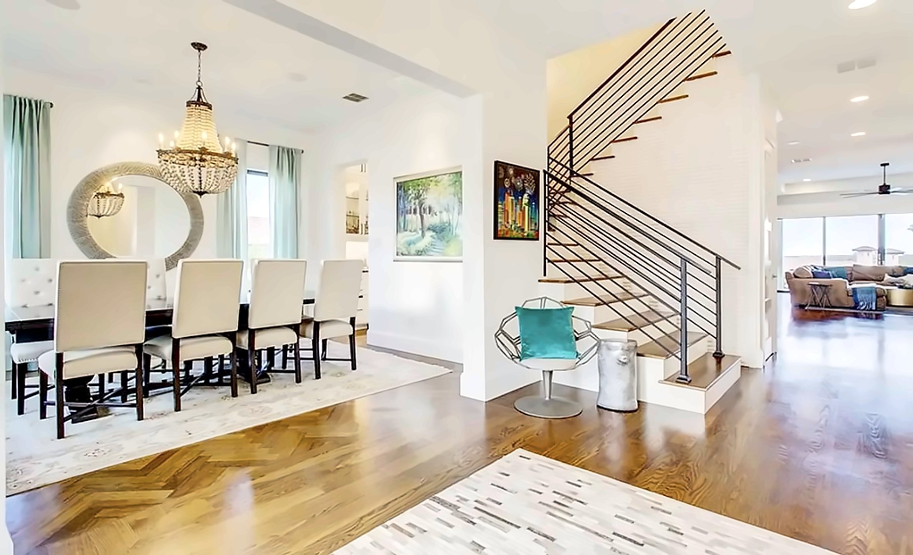 Dining room with a beaded chandelier beside a horizontal-rail stair