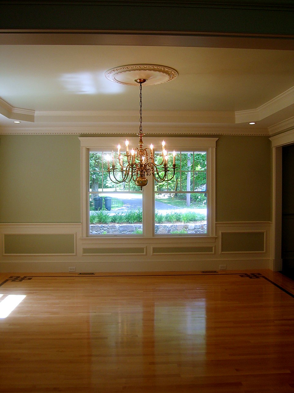 Dining room with a tray ceiling, ceiling medallion, brass chandelier and a Greek-key floor inlay