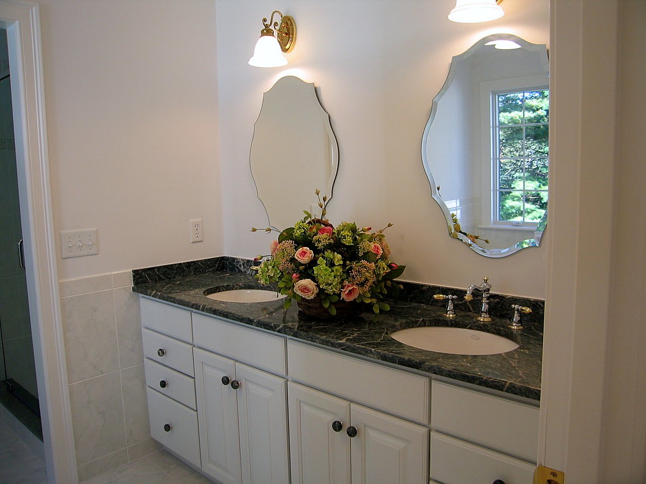 Double vanity with green marble top and scalloped beveled mirrors