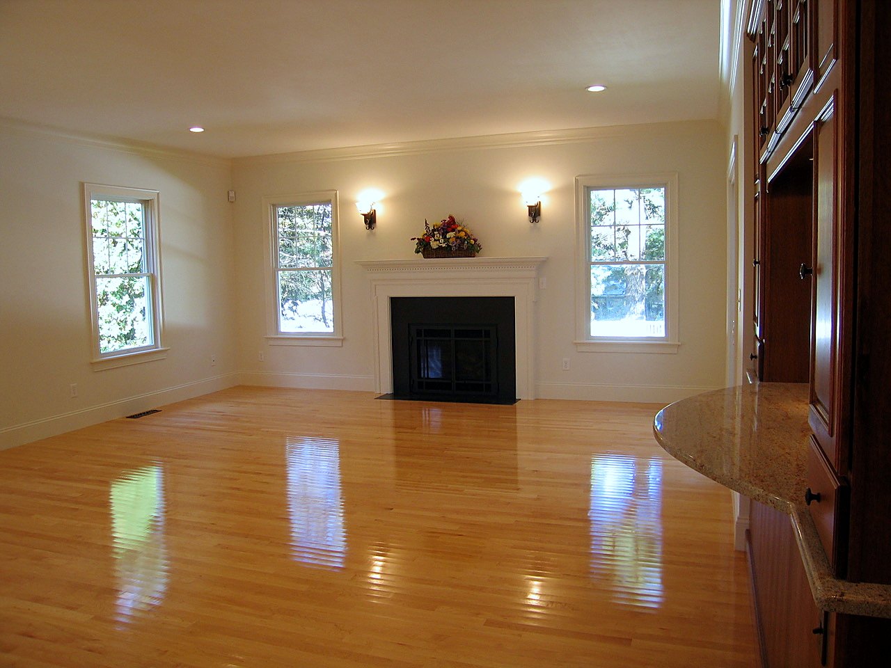 Family room with a dentil-trimmed fireplace mantel between symmetrical windows and sconces