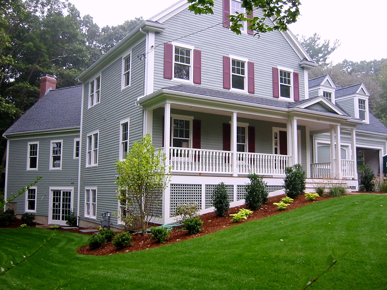 Farmhouse with a wraparound porch, turned balusters and lattice skirting