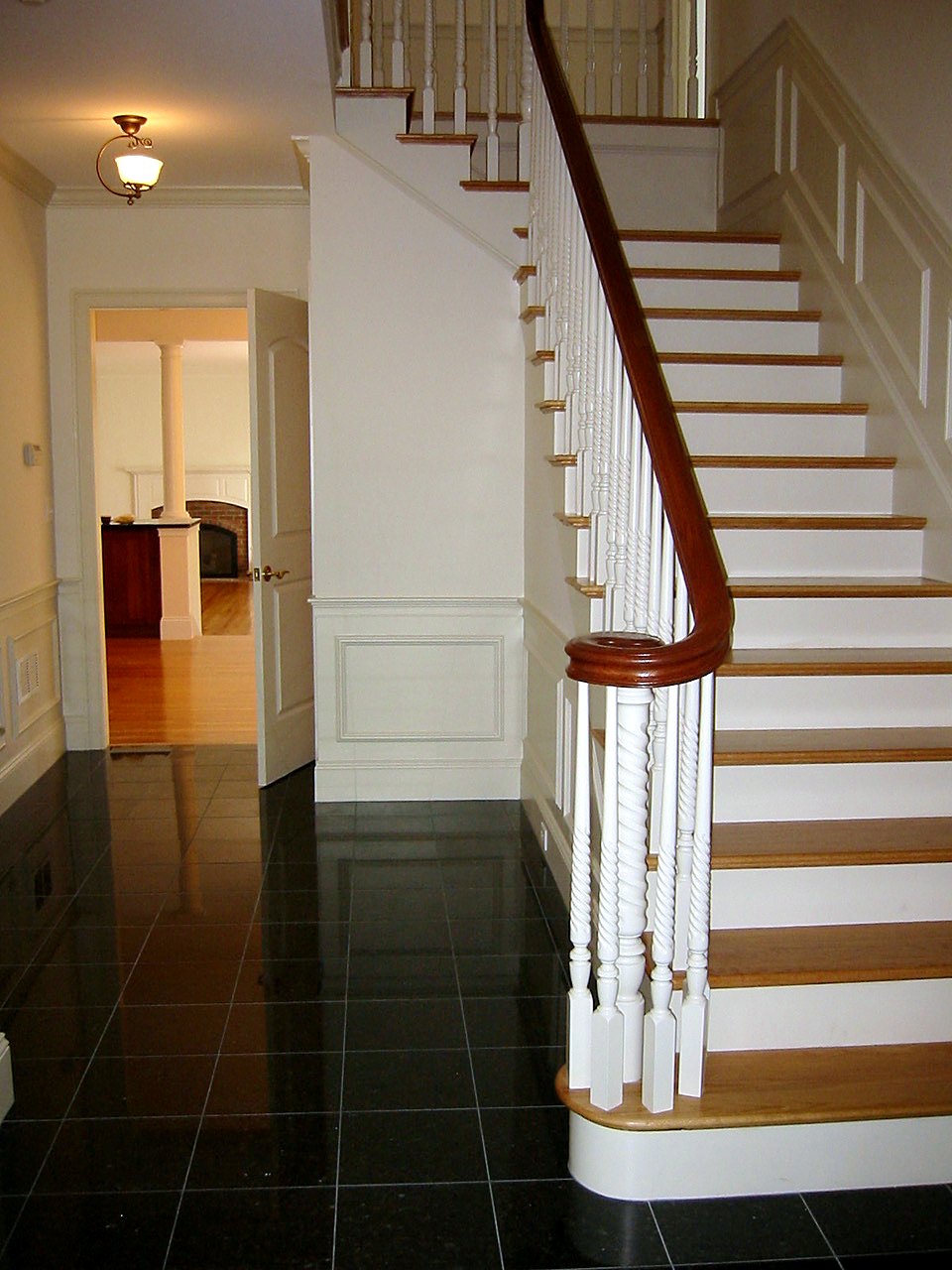 Foyer stair with barley-twist balusters, a volute handrail and black granite floor