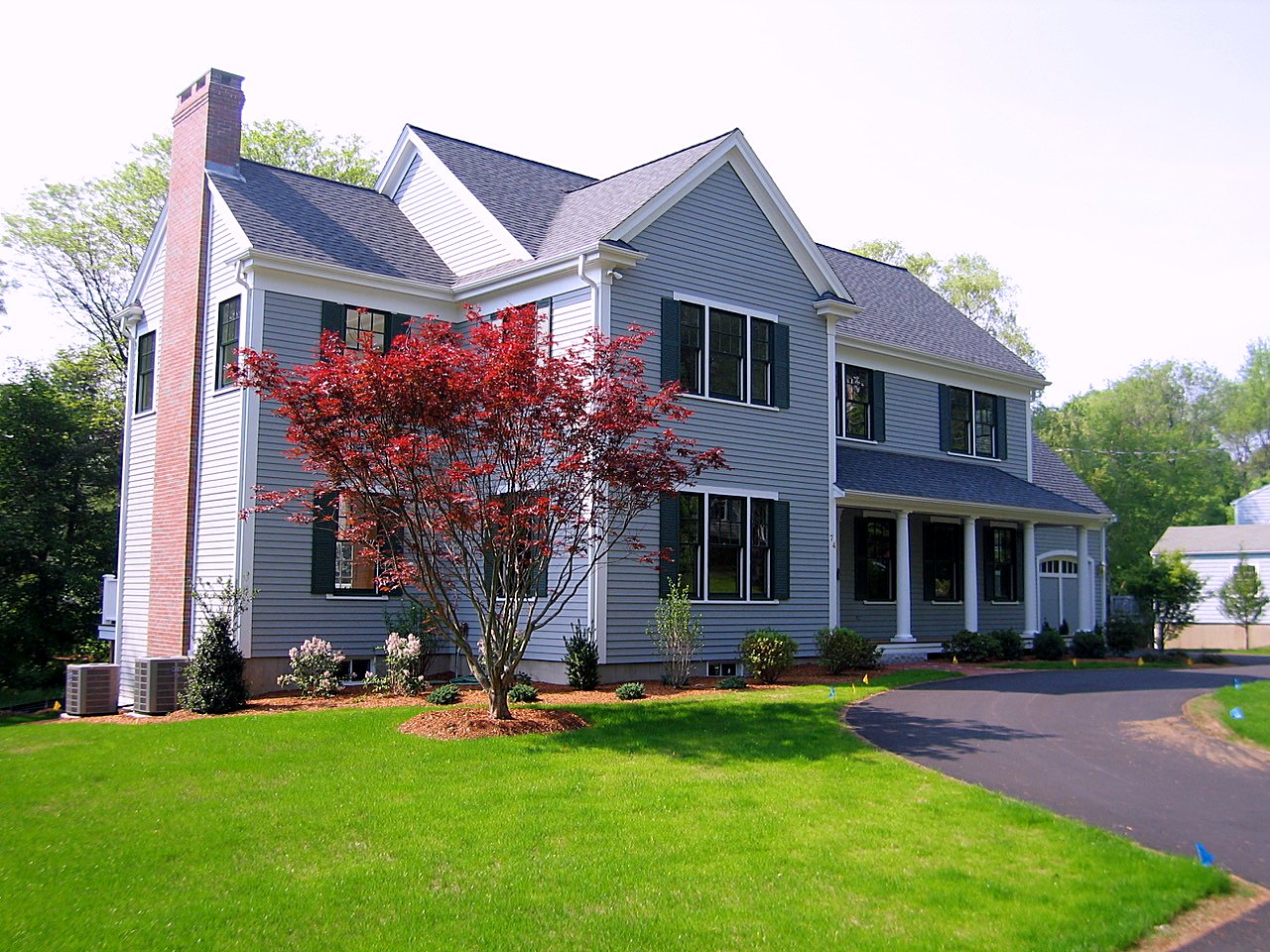 Gray clapboard colonial with green shutters, brick chimney and a red Japanese maple