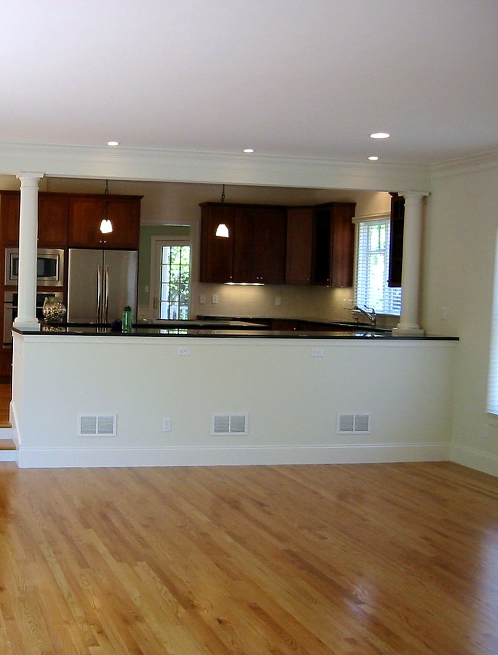 Open kitchen and family room joined by a columned half-wall with a granite counter