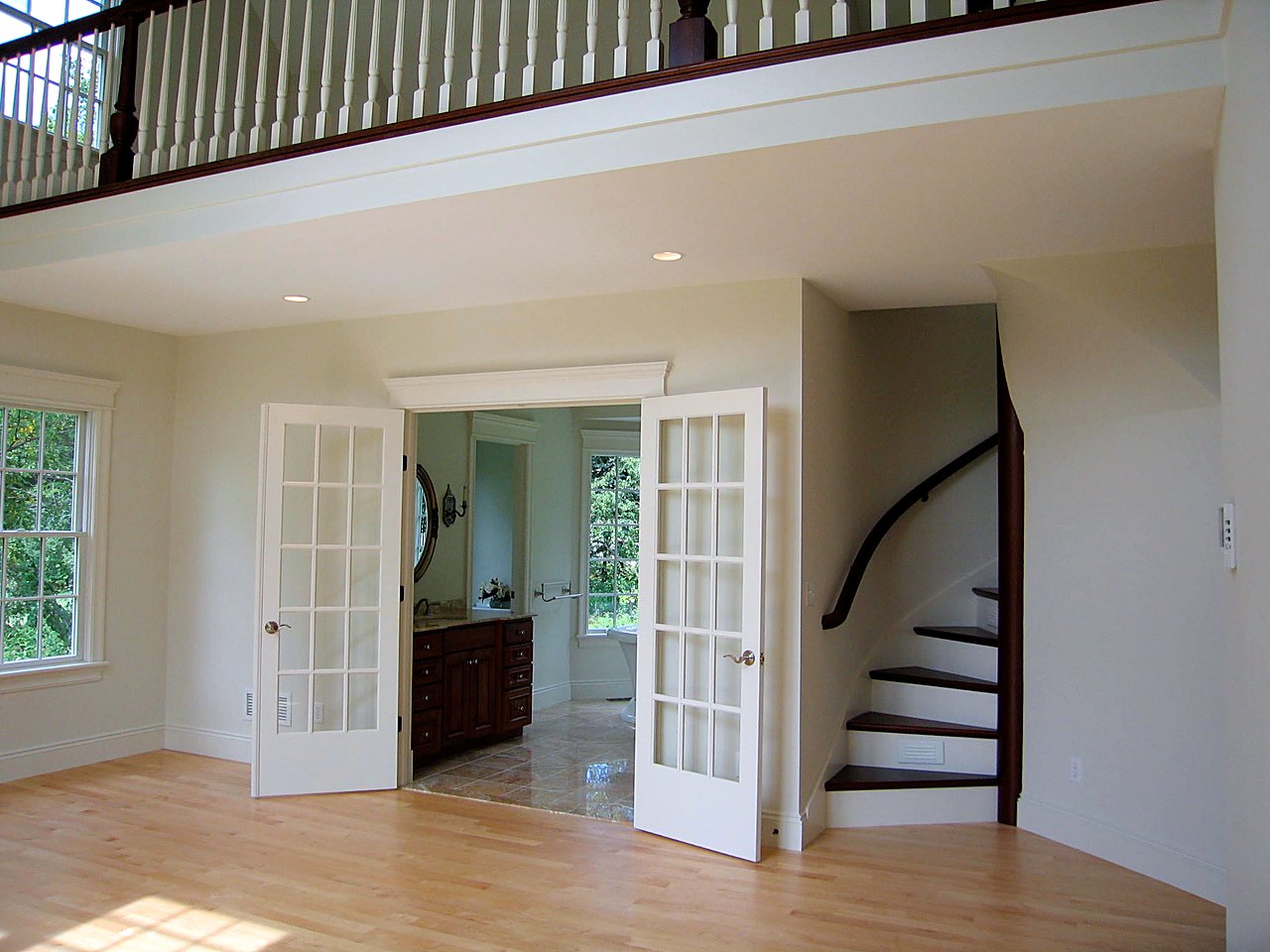 Open loft with French doors and a curved stair with a walnut handrail