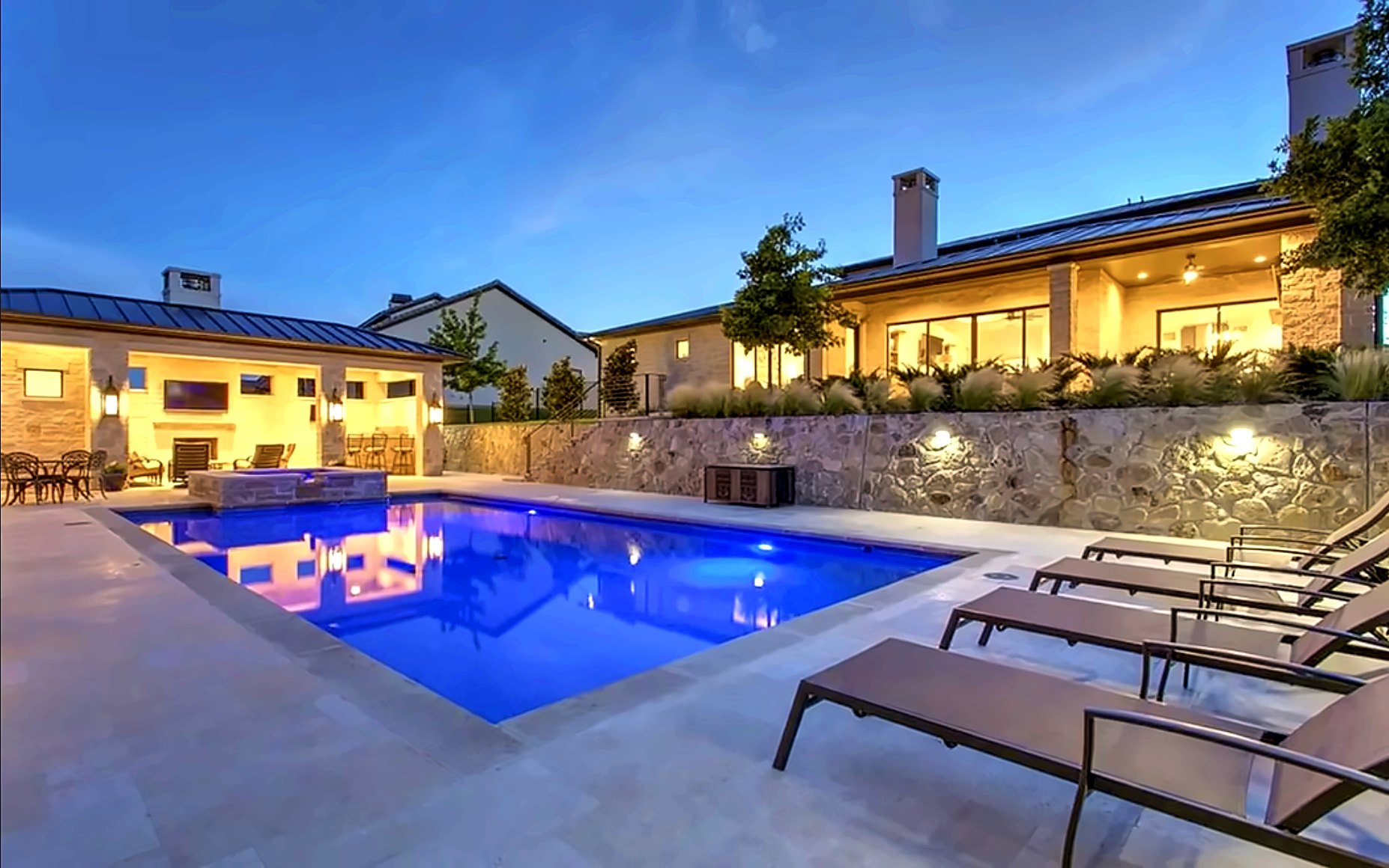 Pool at dusk with the house and pool pavilion lit