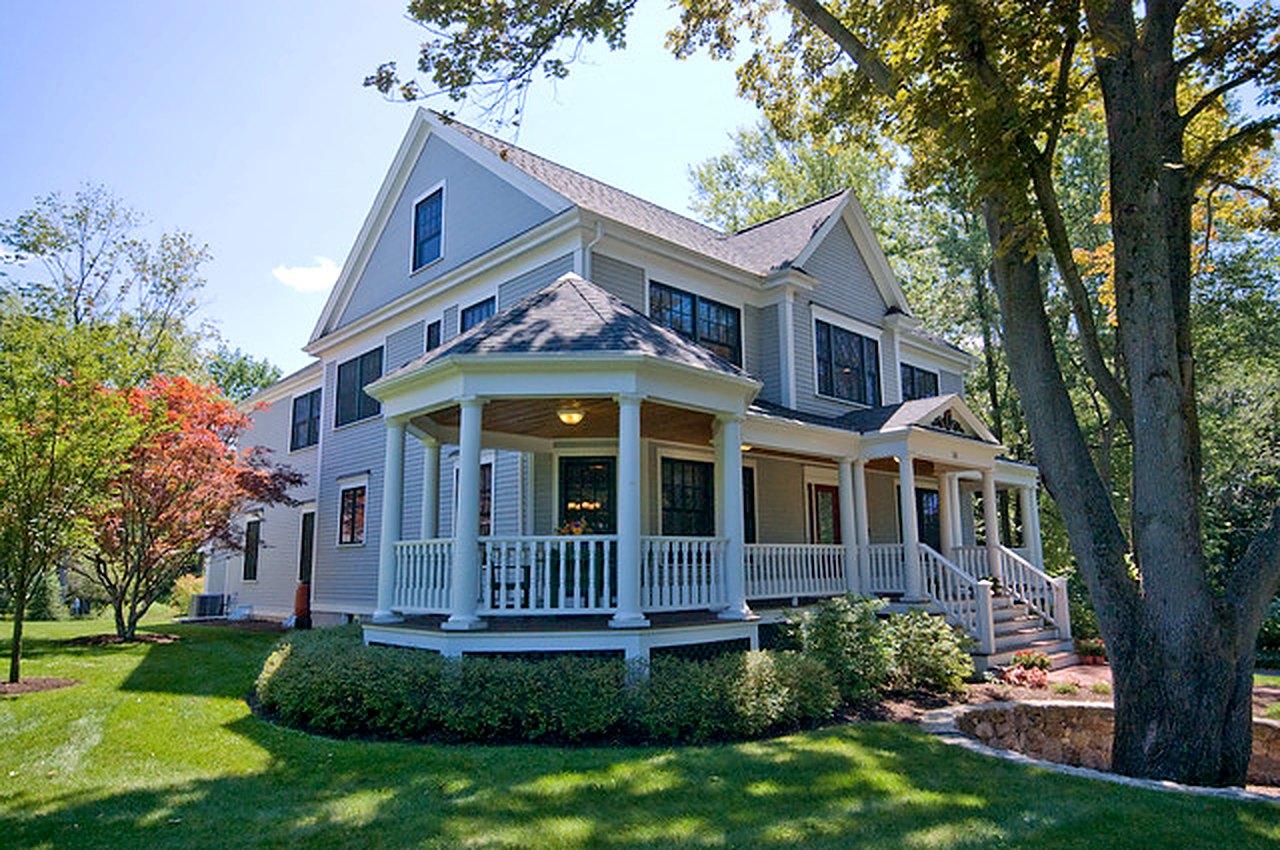Shingle-style home with a wraparound porch, turned columns and white railings
