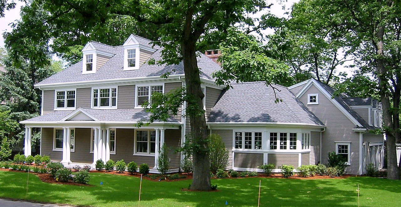 Shingle-style home with dormers, a columned front porch and a curved bay
