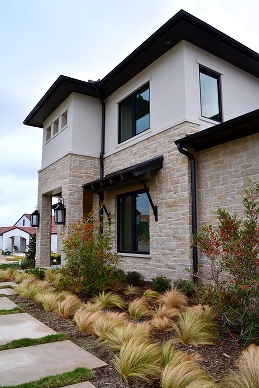 Stone and stucco elevation with lanterns, metal awning and ornamental grasses
