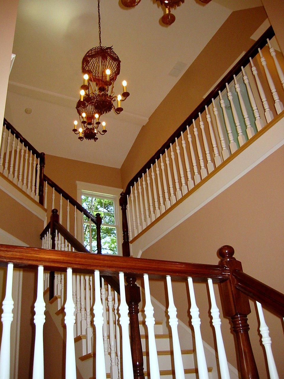 Two-story stair hall with mahogany rails and a candle chandelier