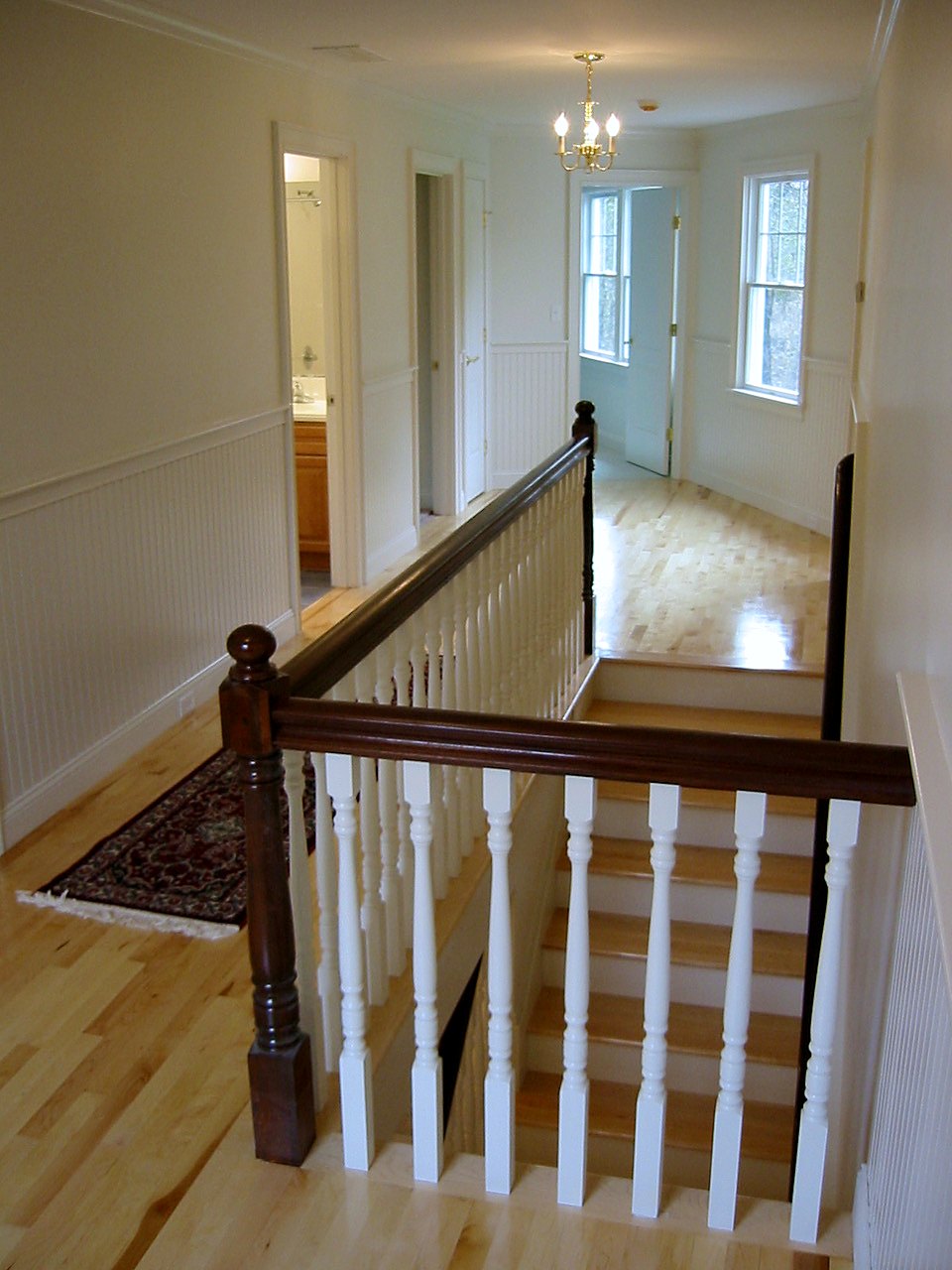 Upper hall with beadboard wainscot and a stair rail with a turned newel