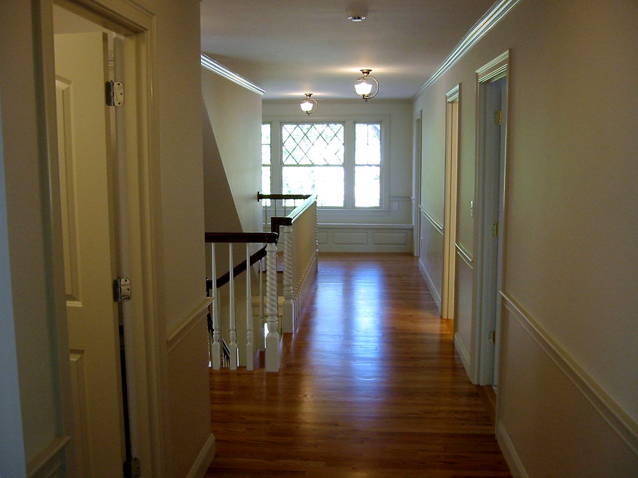 Upper hallway with chair rail leading to a diamond-pane window seat