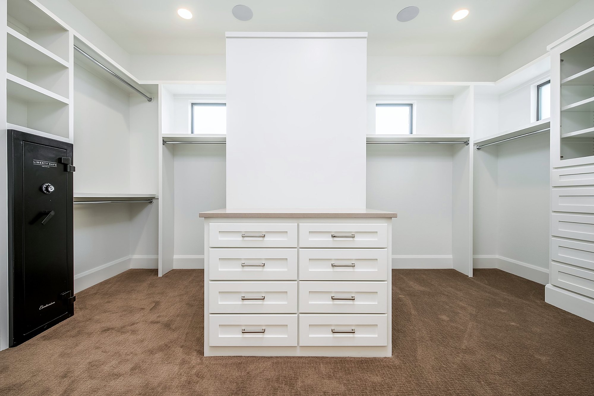 Walk-in closet with built-in shelving and a center island of drawers