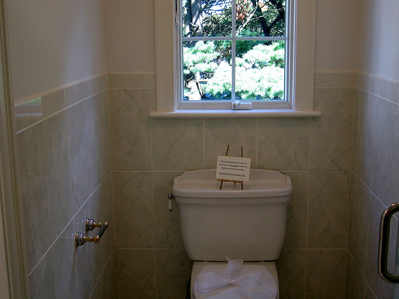 Water closet with marble-look tile wainscot under a garden window