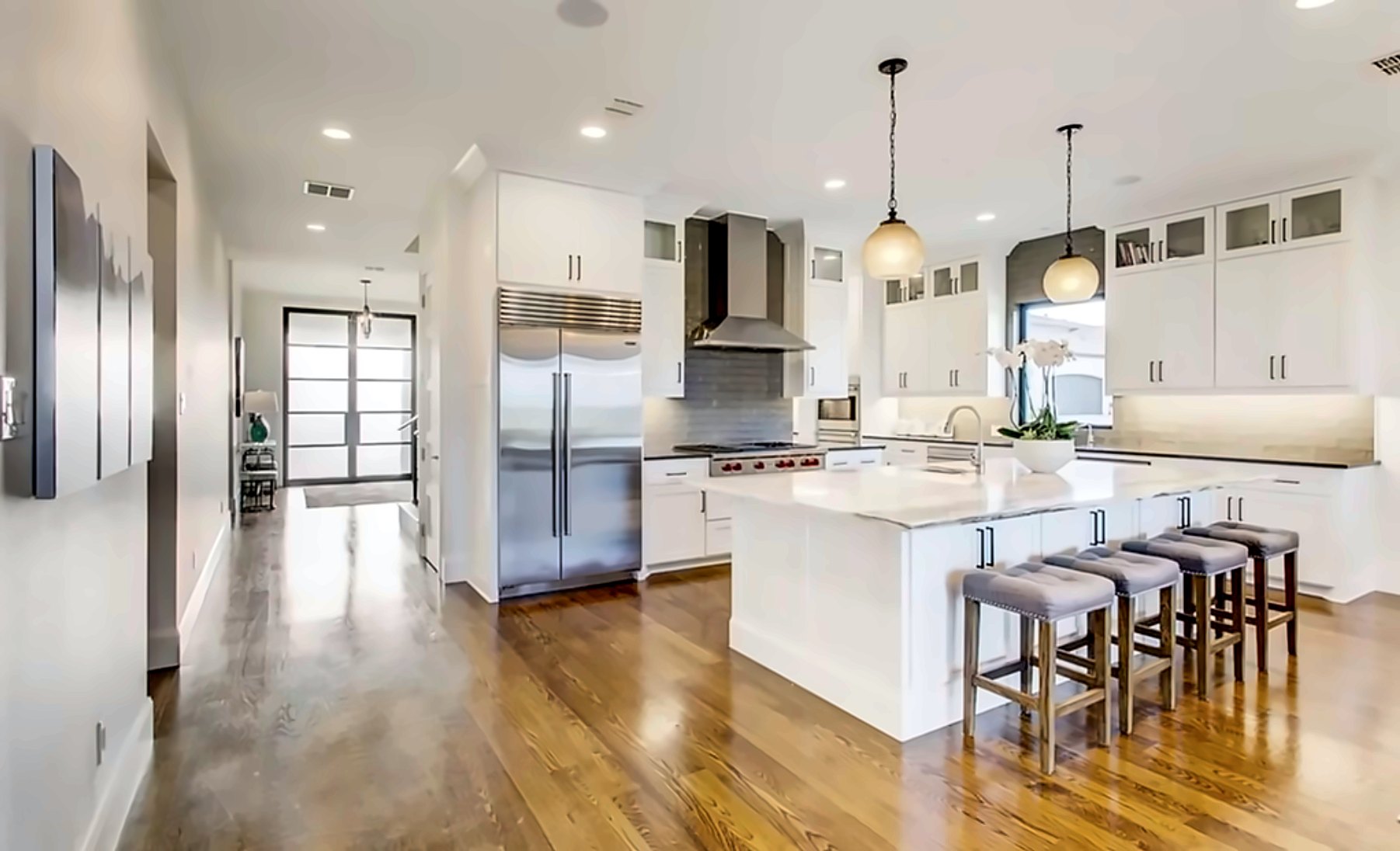 White kitchen with a marble waterfall island and counter stools